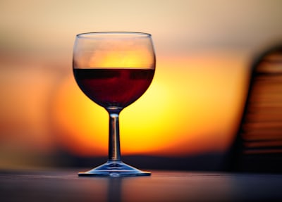 A glass of dark red wine at sunset
